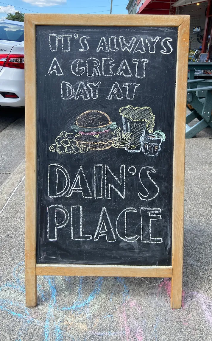 Sandwich board sign with chalk drawing saying It's a Great Day at Dains Place